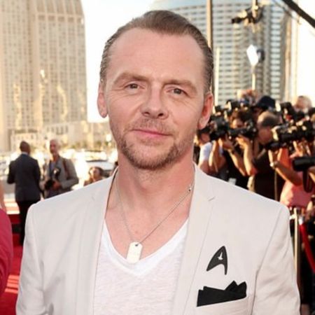 Simon Pegg in a white t-shirt and coat poses at a high-profile event.